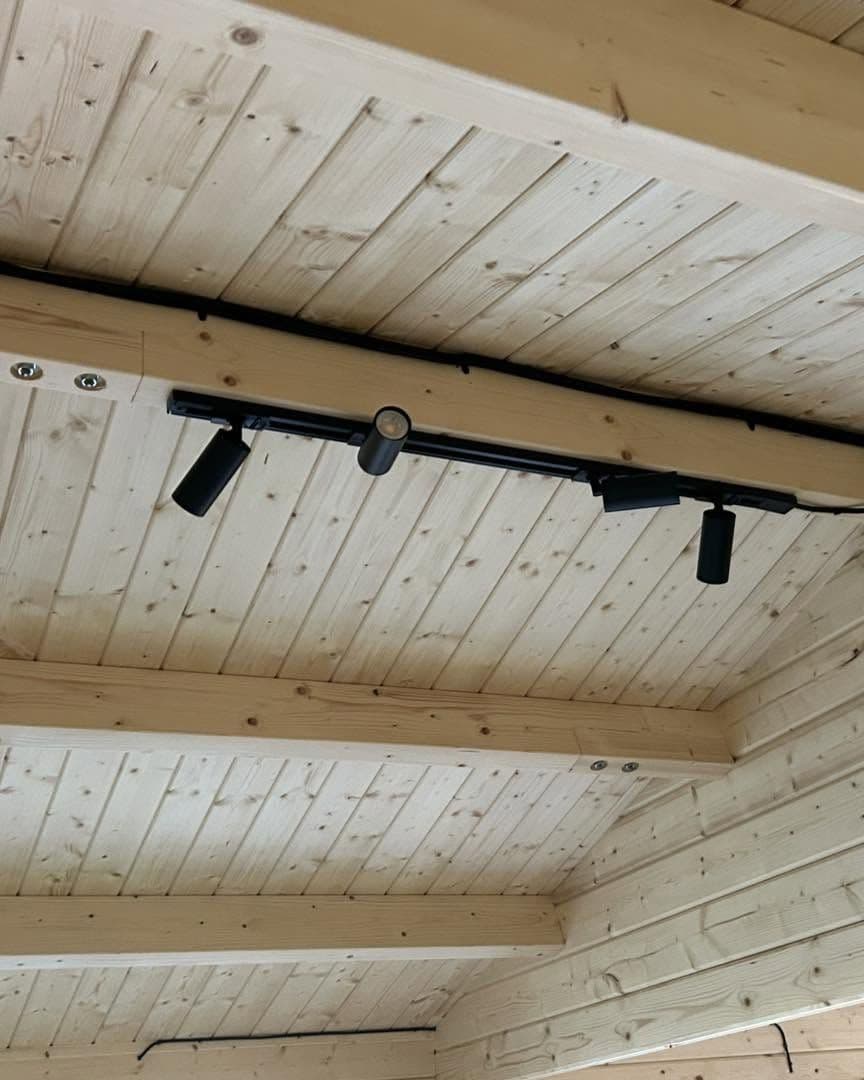 Black track spotlights fitted to a timber-clad garden room ceiling